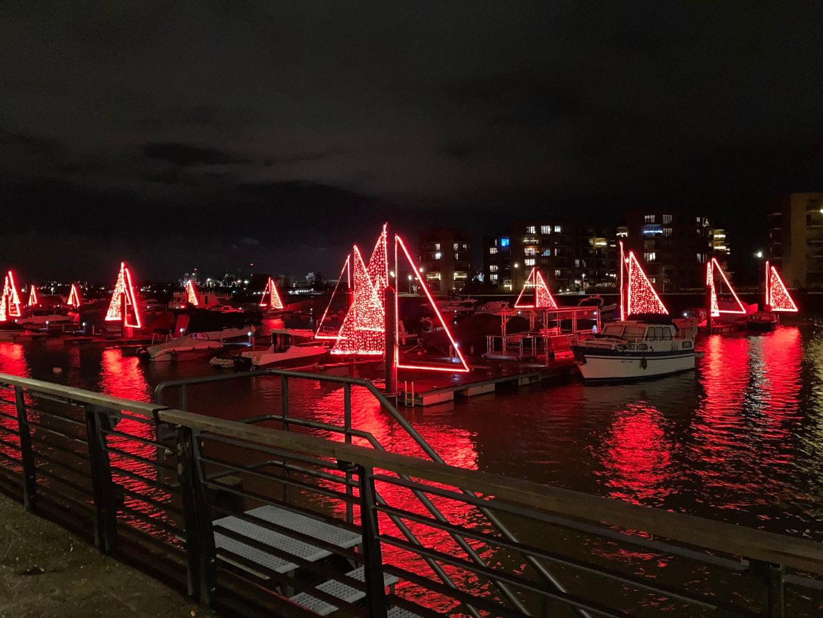 Photo of harbour at night with large sail outlines made of lights.